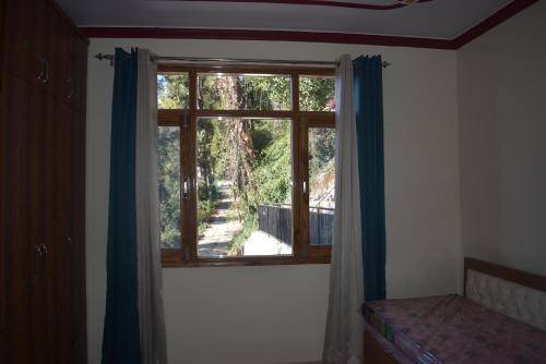 a bedroom with a window with a view of a yard at Fair lawns Home Stay in Shimla