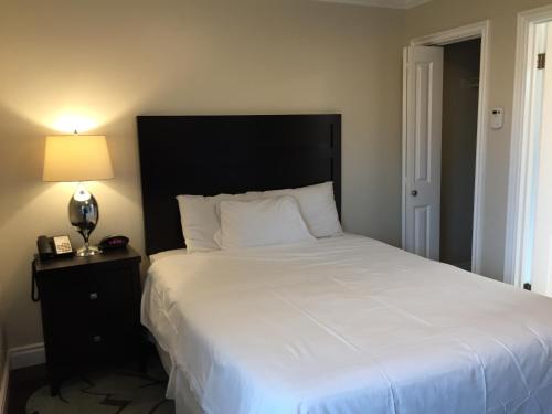 a bedroom with a large white bed and a lamp at Beach Bungalow Inn and Suites in Morro Bay