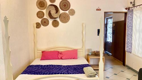 a bedroom with a bed with red pillows and plates on the wall at Le Colibri Guesthouse in Cotonou