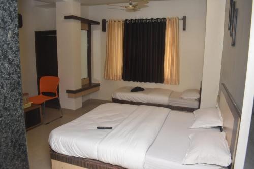 a bedroom with two beds and a chair in it at HOTEL SAI VISHVA KARMA in Shirdi