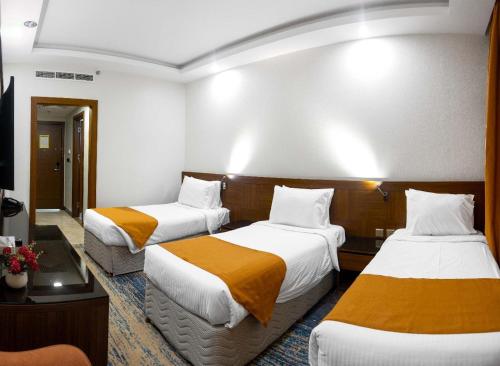 a hotel room with two beds with orange sheets at Emaar International in Mecca