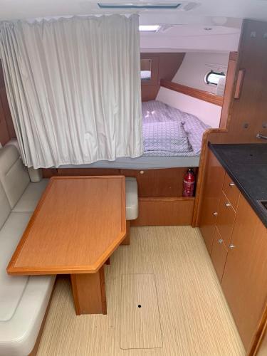 Cette petite chambre comprend un lit et une table dans un bateau. dans l'établissement BOAT PARADISE LA ROCHELLE - Bavaria 31 Sport, à La Rochelle