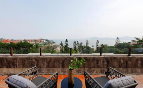a patio with two chairs and a table with a vase at Linggan Linghai Hotel in Xiamen