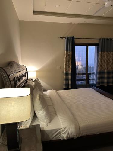 a bedroom with a white bed with a window at 2 Bedroom Appartment Near Airport & Moterway in Islamabad