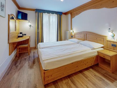 a bedroom with a large bed and a desk at Hotel Madonna delle Nevi in Folgarida