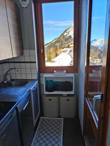Il comprend une cuisine avec un évier et une fenêtre donnant sur la montagne. dans l'établissement Appartement 5 p Belle Plagne Skis aux pieds, à Belle Plagne