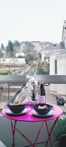 une table rose avec deux assiettes et des verres à vin sur un balcon dans l'établissement Studio Château Durieux 2 centre-ville proche thermes idéal vacances et cure thermale, à Aix-les-Bains