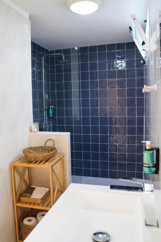 a bathroom with a blue tiled shower with a basket at Seashore Villa - Porto Santo in Porto Santo