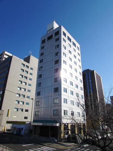 a tall white building in front of some buildings at APA Hotel Mito-Ekimae in Mito
