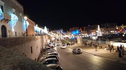 a city at night with cars parked on the street at A Soqquadro in Bisceglie