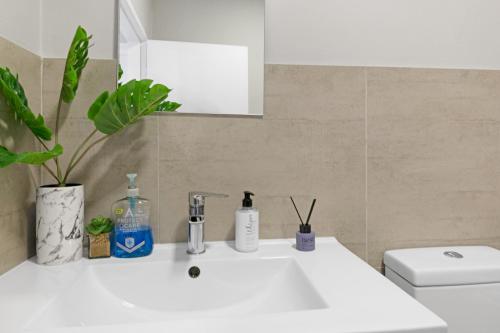 a bathroom with a white sink and a toilet at Two Bedroom Luxury Apartment, Century City - BackUp Power in Cape Town