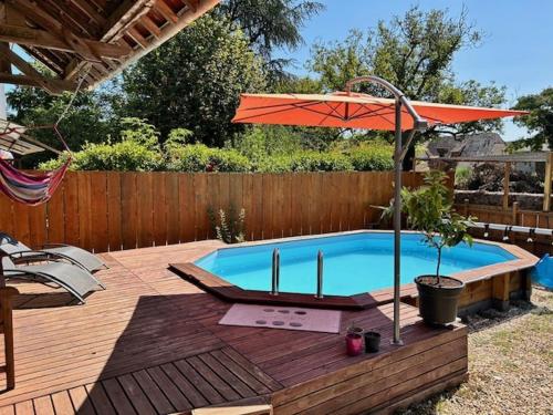 - une piscine avec un parasol sur une terrasse en bois dans l'établissement Gîte : La Petite Grange, à Valojoulx
