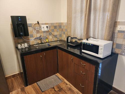 a kitchen with a microwave on a counter with a sink at Coastal Suites Apart Hotel ---- 8 minutes walk to beach in Benaulim