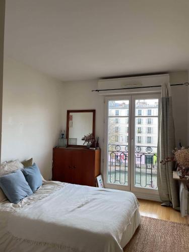 une chambre avec un lit et une grande fenêtre dans l'établissement Appartement spacieux et lumineux - Canal Saint Martin, à Paris