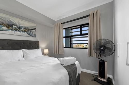 a bedroom with a bed with a fan and a window at Two Bedroom Luxury Apartment, Century City - BackUp Power in Cape Town