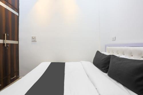 a white bed with black pillows in a bedroom at Hotel O Golden Key Rohini in New Delhi