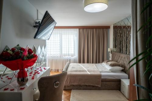 a bedroom with a bed and a table with a vase of flowers at GORSKI RESORT Lux Apartments Jacuzzi & Sauna in Poronin
