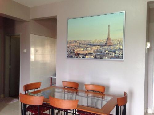 a dining room table with chairs and a picture of the eiffel tower at Noah's Homestay in Shah Alam