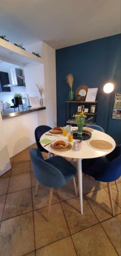 une salle à manger avec une table blanche et des chaises bleues dans l'établissement Le Metz Calais-Nord - Balcon -Plage -Commerces, à Calais