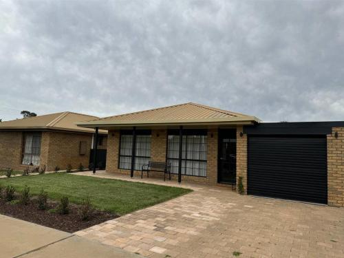 a brick house with a gate and a garage at Interior Stylist's Country Unit in Nhill