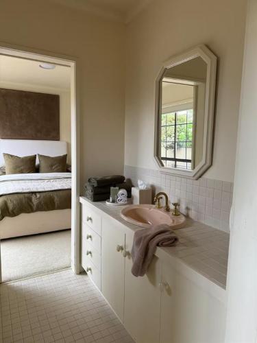 a bathroom with a sink and a mirror and a bed at Interior Stylist's Country Unit in Nhill