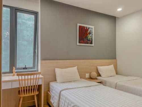a room with two beds and a chair and a window at Lux Nest hotel in Ấp Kim Thạch