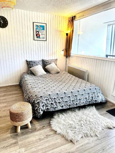 - une chambre avec un lit, un tapis et un tabouret dans l'établissement Appartement cosy Centre station de Super Besse pour 2 à 6 personnes, à Besse-et-Saint-Anastaise