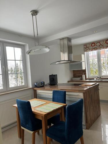 a kitchen with a wooden table and blue chairs at B-Willa Słopnice basen & jacuzzi, sauna in Słopnice
