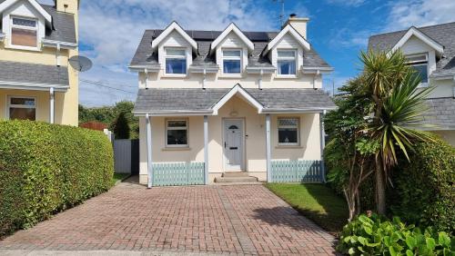 a white house with a brick driveway at Curracloe Beach House in Curracloe