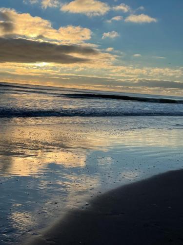 a beach with the reflection of the sky in the water at Curracloe Beach House in Curracloe