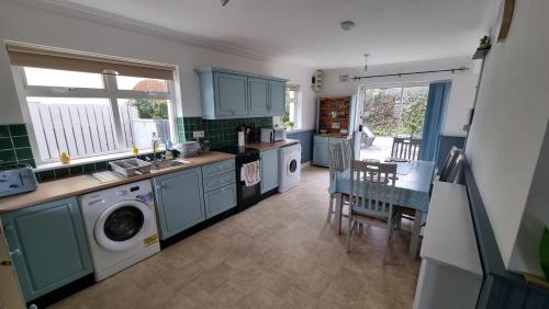 a kitchen with blue cabinets and a table and chairs at Curracloe Beach House in Curracloe