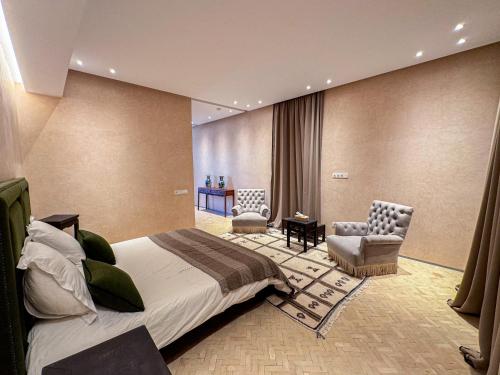 a bedroom with a bed and two chairs in a room at Atlas Retreat Luxury Bed and Breakfast in Beni Mellal