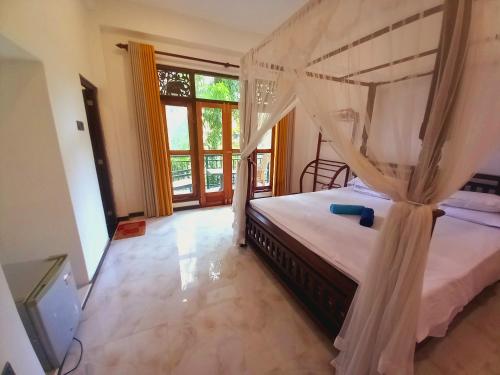 a bedroom with a canopy bed and a television at Mount Edge Villa in Unawatuna