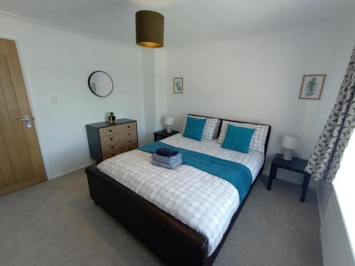 a bedroom with a large bed with blue pillows at 3BR House with garden near Bicester Village in Bicester