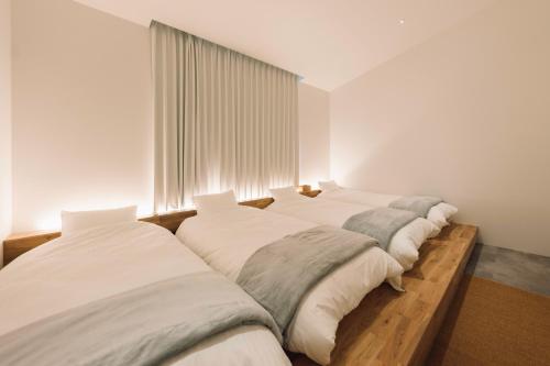 a row of four beds in a room at ACOA Villa Takashima in Takashima