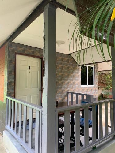 a porch with a white door and a brick wall at Krua Chehe Resort ครัวเจ๊ะเห รีสอร์ท in Ban Khok Muang