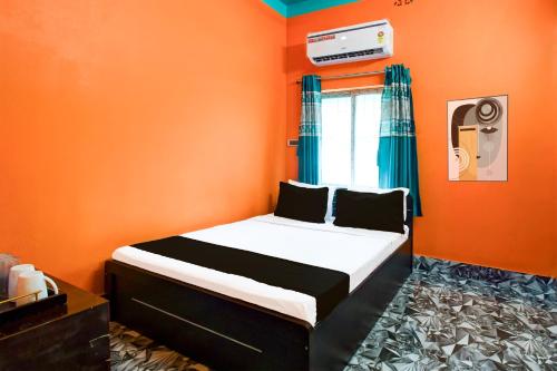 a bedroom with a bed in an orange room at Hotel O by OYO ALO Hotel in Phulbāri
