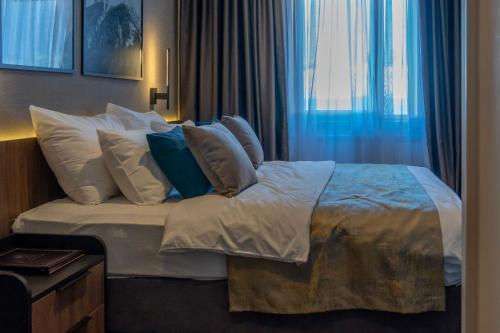 a bedroom with a bed with pillows and a window at Hotel Rajska dolina Jahorina in Jahorina