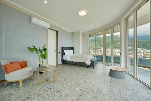a bedroom with a bed and a chair and windows at Панорамная квартира на первой линии моря Skyline Resort, Becici, Budva in Becici