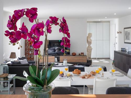 - un salon avec une table ornée de fleurs violettes dans un vase dans l'établissement La dame de France - Perpignan, à Perpignan