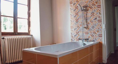 une grande baignoire dans une salle de bain avec une fenêtre dans l'établissement Domaine de Maisonneuve, à Sugères