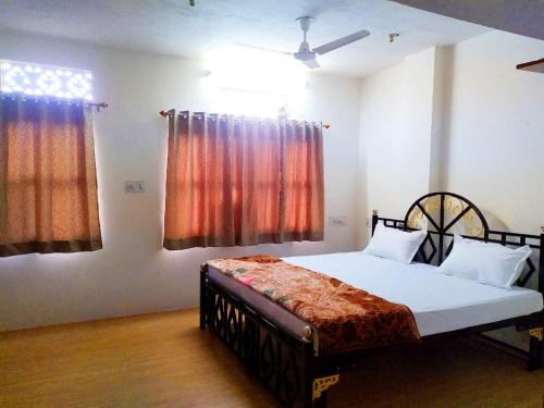 a bedroom with a bed and two windows at Vasu Vijay Stays in Udaipur