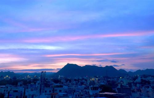 a view of a city at sunset with mountains at Vasu Vijay Stays in Udaipur