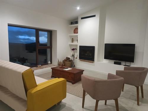 a living room with a tv and a couch and chairs at Masia La Canyada in Villafranca del Cid