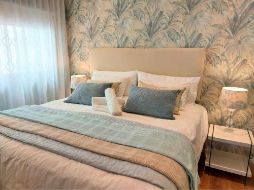 a bedroom with a large bed with blue pillows at Mouille Point Seafront Cottage in Cape Town
