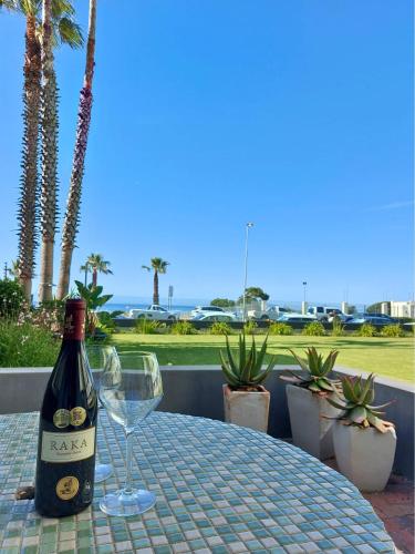 a bottle of wine sitting on a table with a glass at Mouille Point Seafront Cottage in Cape Town