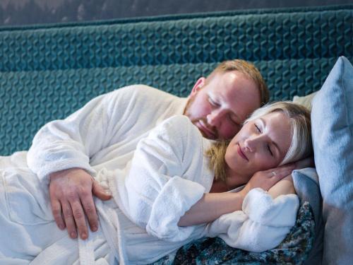 a man and a woman laying on a bed at Panoramahotel Grobauer in Spiegelau