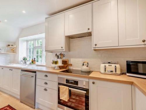Oak Tree Cottage في Lincolnshire: مطبخ بخزائن بيضاء وفرن موقد