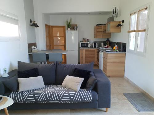 un salon avec un canapé bleu et une cuisine dans l'établissement LA TUILIÈRE : Détente Cocooning spa, à Courthézon