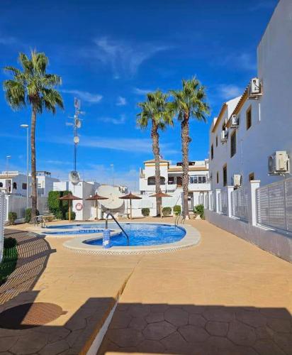 a swimming pool with palm trees next to a building at Casita Stam Orihuela in Orihuela